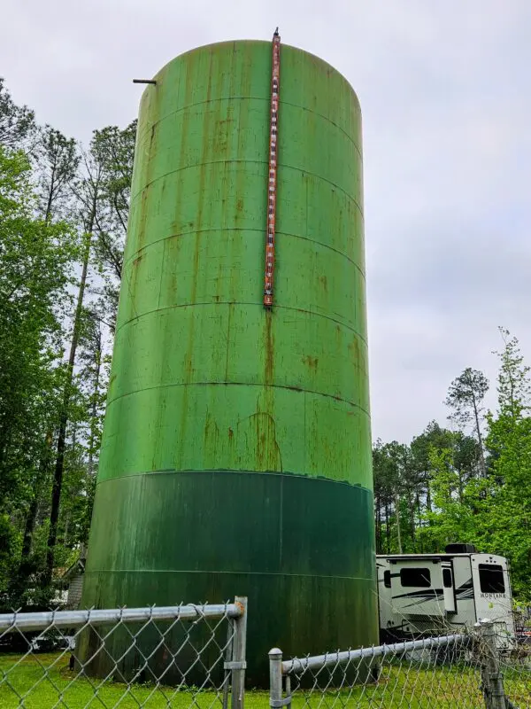 A large green tank sitting next to trees.