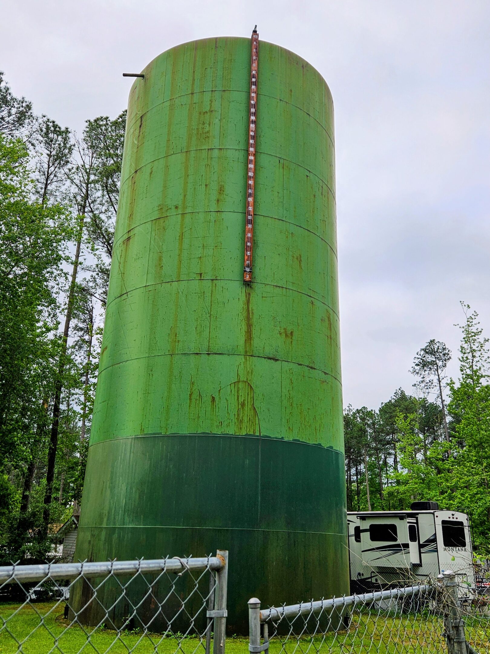 A large green tank sitting next to trees.