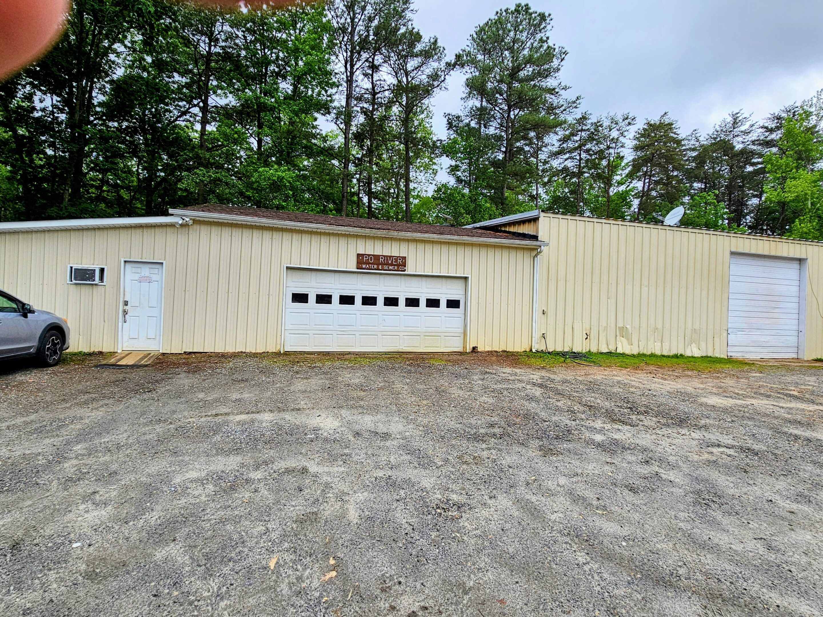 21777050-a108-4e2a-a447-dccd0e7812a8-7b8f4bf7-1f29-49cb-88b1-87553bace2c1~2 A large garage with two doors and trees in the background.