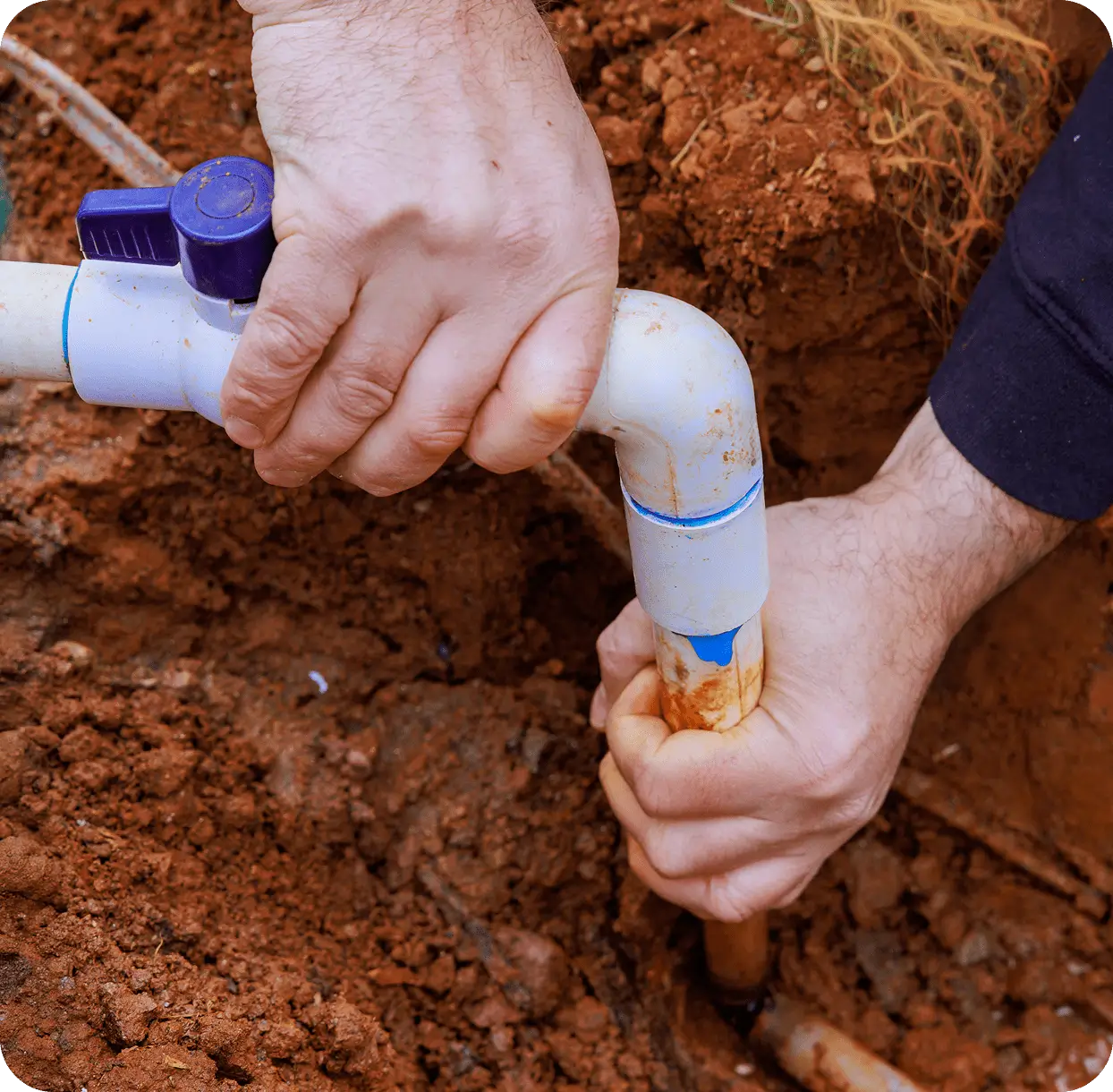 Hands repairing underground PVC water pipe.